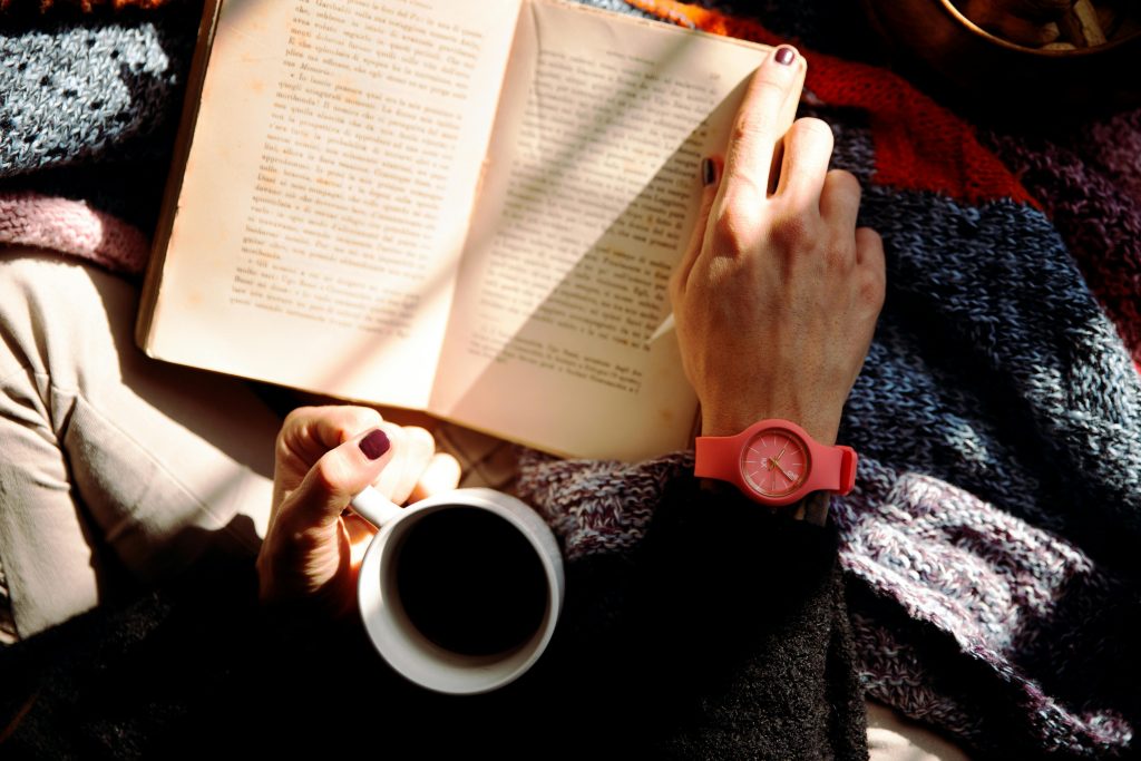 pexels-photo-1550648-1550648 Woman relaxing with a book and coffee in a sunlit cozy setting, wearing a stylish watch.