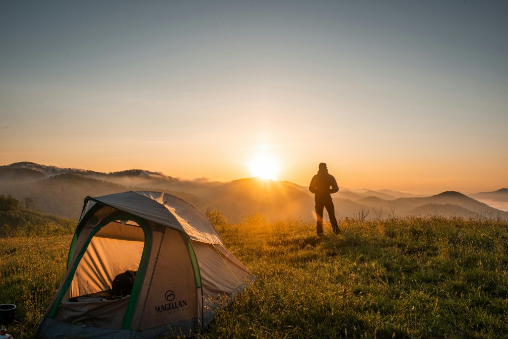 pexels-photo-2398220-2398220 A camper enjoys the sunrise in a mountain setting with a tent. Perfect nature escape.